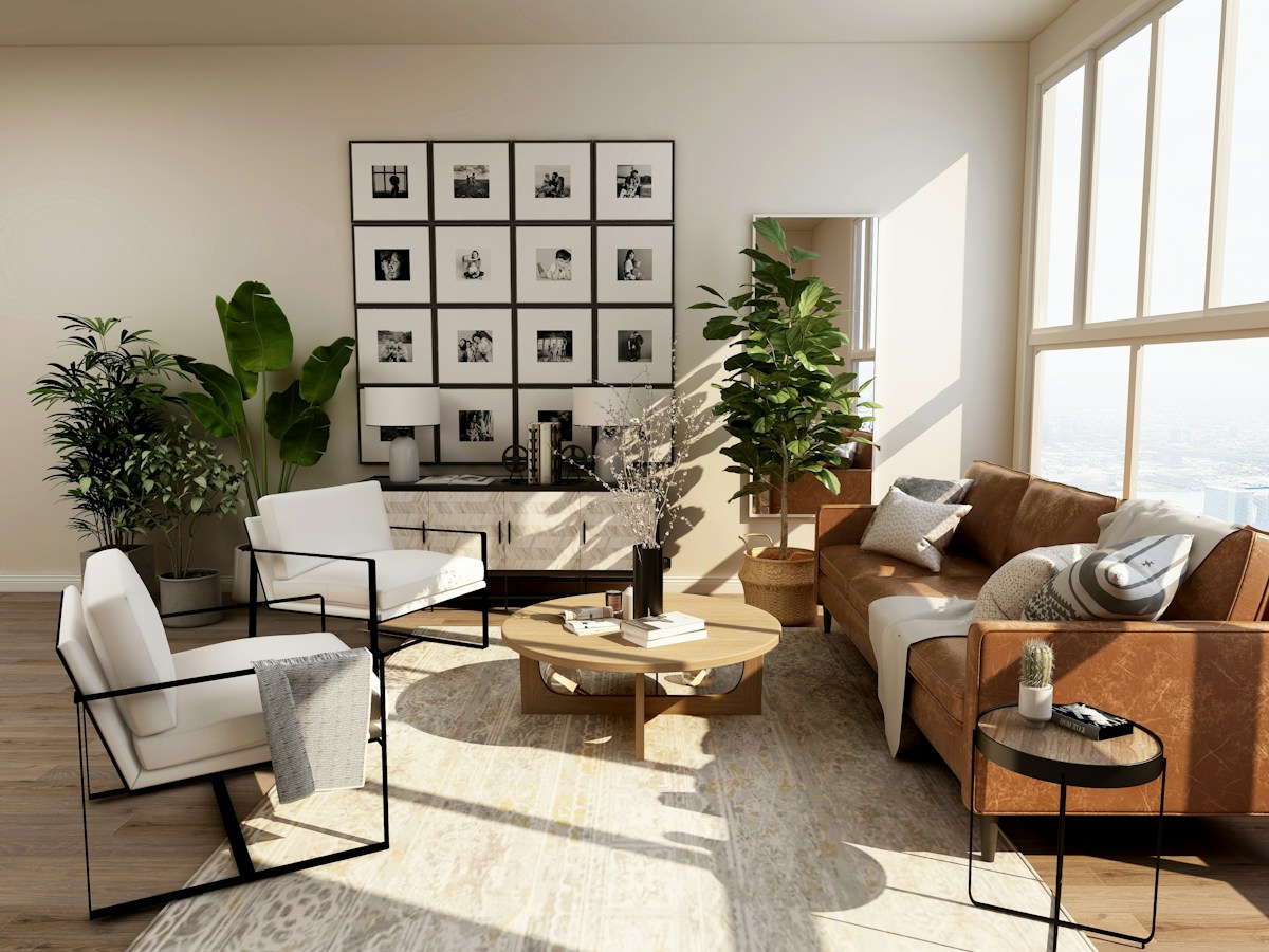 A sunlit neutral interior with seating, indoor plants and framed photographs